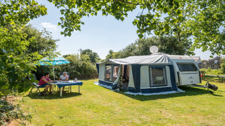 Caravane installée sur un emplacement herbeux au camping La Guyonnière